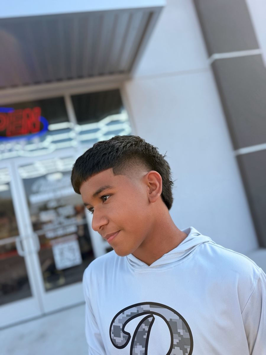 Client with a textured mullet and burst fade, photographed outside the studio
