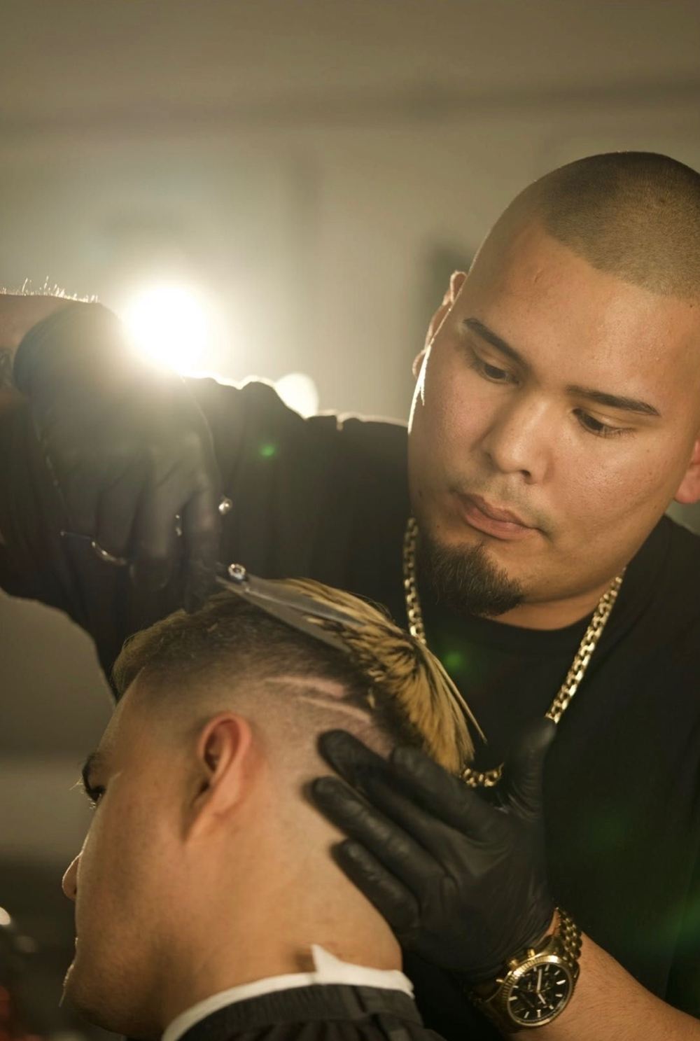 Jaydee Hernandez in black gloves, cutting a client's hair with scissors